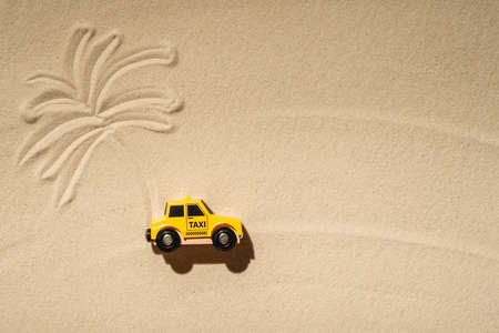 Toy taxi car, sun, palm tree on beach sand. Concept. Fast and cheap taxi booking service. Travel. Summer time. Creativeの写真素材