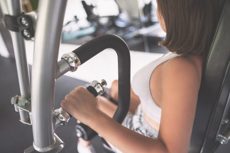 Sporty young woman doing arms exercises on the simulator in the gym. Cropped. Health concept....