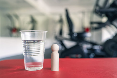 Wooden people man standing near big glass of still water in fitness gym opposite the sport...