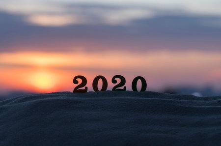 Silhouette of 2020 wooden numbers on the sand on the beach at sunset. Setting sun. The symbol of the...