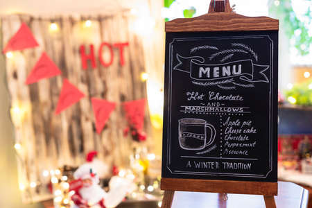 Woman drawing christmas menu of cocoa bar on small chalkboard.の写真素材