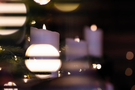 Selective focus of burning candle in Christmas decoration with light bokeh. Close up