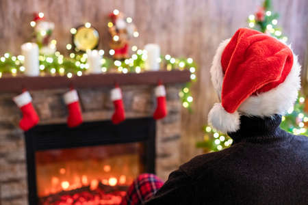 Back view of sad man in santa claus hat in a depression feeling negative emotions during christmas celebrationsの写真素材