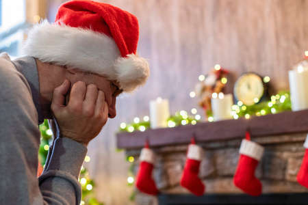 Sad man in Santa Claus hat in a depression feeling negative emotions during christmas celebrationsの写真素材