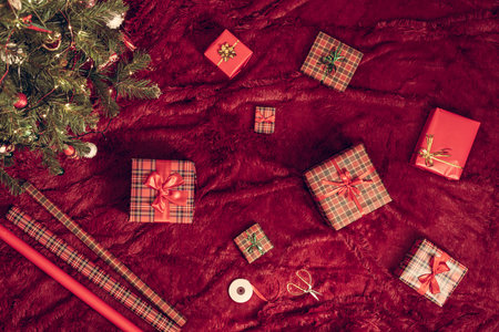 Wrapped christmas gifts boxes for family lying on fluffy plaid near christmas tree. Top view, flat layの写真素材