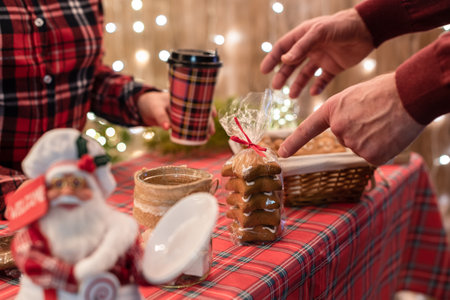 Man customer buying coffee latte in a paper cup pointing finger on gingerbread cookies at the christmas bakery.の写真素材