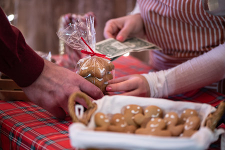 Man customer buying christmas sweets at the bakery giving dollars to the woman sellerの写真素材