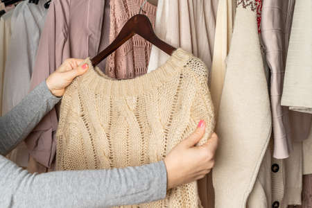 Woman shopper, customer choosing clothes. Assortment of female modern summer and autumn clothing in garment store. Shopping.の写真素材