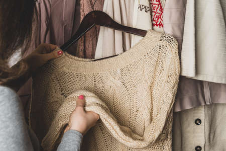 Woman shopper, customer choosing clothes. Assortment of female modern summer and autumn clothing in garment store. Shopping.の写真素材
