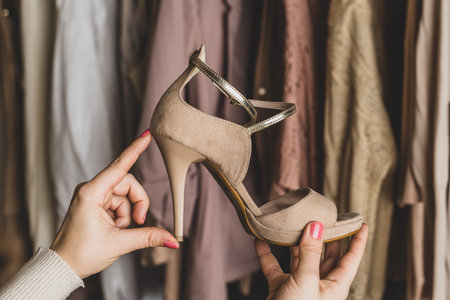 Woman shopper, customer measuring high-heeled shoes choosing footwear, clothes from assortment of...