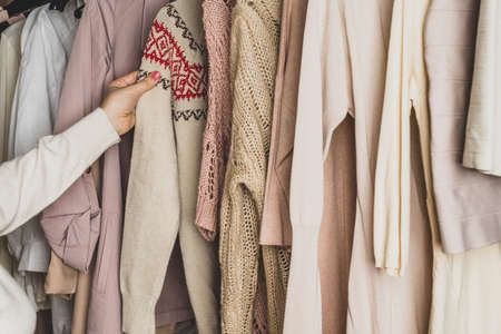 Woman shopper, customer choosing winter pulover with chtistmas ornament from assortment of clothing in garment store. Shopping. Winterの写真素材