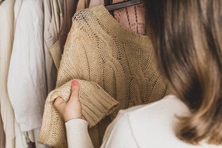 Woman customer checking the material choosing woolen sweater from in garment store. Shopping.