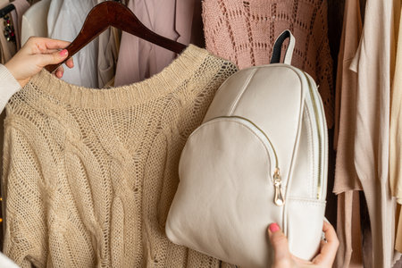 Woman shopper, customer choosing small leather backpack, clothes. Assortment of female clothing in garment store. Shopping.の写真素材