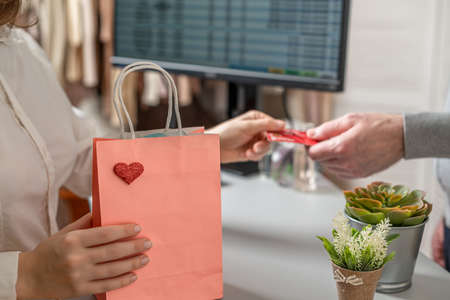 Man with credit card pays at the checkout buying gift in a female clothing store.の写真素材