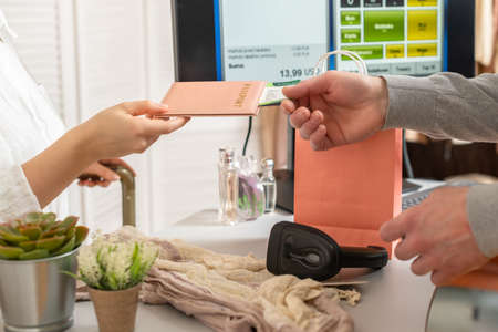 Woman holding out passport with boarding pass to cashier in female boutique store at the airport duty free.の写真素材