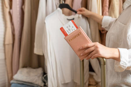 Woman with suitcase holding passport with boarding pass in female boutique store at the airport duty freeの写真素材