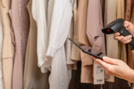 Female entrepreneur holding tablet, barcode scanner while doing inventory in her trendy clothing...