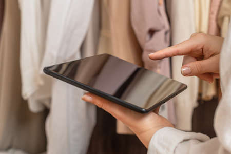 Female entrepreneur holding tablet while doing inventory in her trendy clothing shopの写真素材