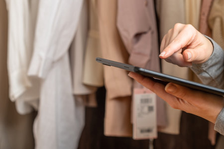 Female entrepreneur holding tablet while doing inventory in her trendy clothing shop