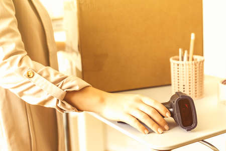 Female owner of start up small business using barcode scanner scanning retail drop shipping package postal parcel bar code. Warehouse worker.の写真素材