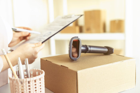 Female owner of start up small business with clipboard and barcode scanner in a small office....