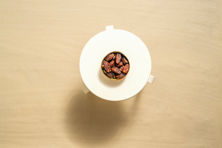 Royal dates fruit in a bowl of coconut on the white table on the sandy beach. Summer vacation. Top viewの写真素材