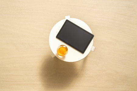 Tablet, orange juice on the table on the sand of beach. copy space. Top view. Selected focus