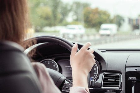 woman is driving on the highway. View from the back seat of the car