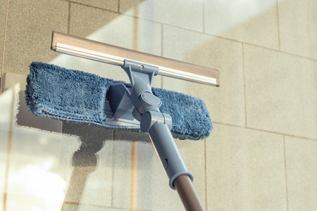 Girl Cleaning open Window of balcony by spraying Cleaning Products and wiping with mop Sponge at the summer sunset evening.の写真素材