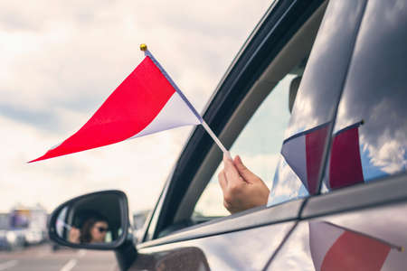 Woman or Girl Holding Indonesia Flag from the open car windowの写真素材