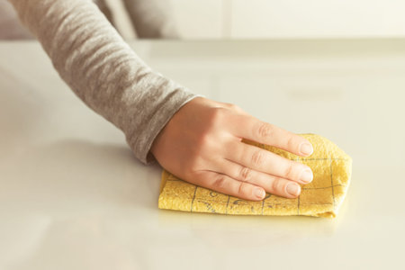 Cleaning wipe with a cloth in the hands of woman kitchen table. Housekeeping service. The concept of...