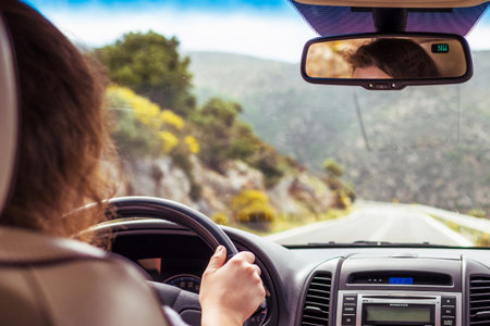 Woman driving a car relaxing in auto trip traveling along ocean tropical beach in background....