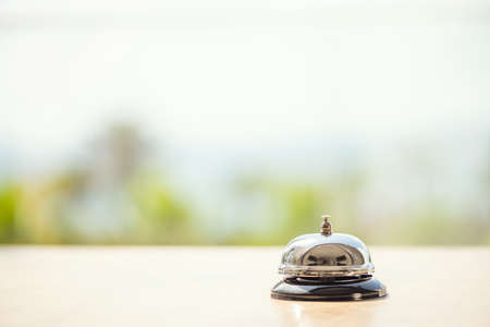 The desk cafe, restaurant with a service bell for warn that the dish is ready. Roof of beach cafe with sea and palm tree viewの写真素材