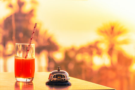 The desk cafe, restaurant with a service bell for warn that the beverage is ready. Table reservation for dinner. Roof of beach cafe sea and palm tree view on sunset.の写真素材