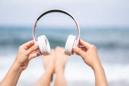 Woman hands with headphones on a beach and sea coastline.の写真素材
