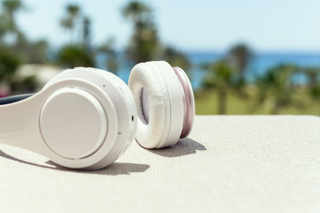 Headphones on the table in the palm tree forest. Summer vocation. Listen music. Close up. Cropped. Conceptの写真素材