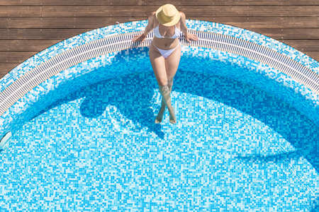 Young alone beautiful sports woman in bikini and hat is swimming in . Aerial drone view from above. Tropical summer luxury hotelの写真素材