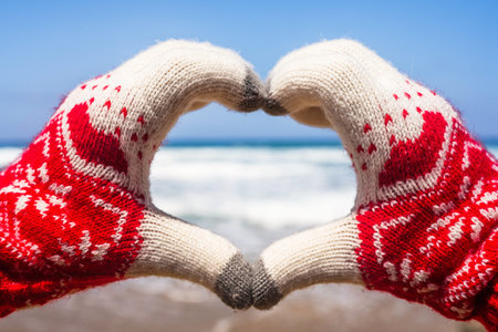 Christmas sea holiday. Happy woman in gloves showing heart shape from hand and relaxing on paradise...