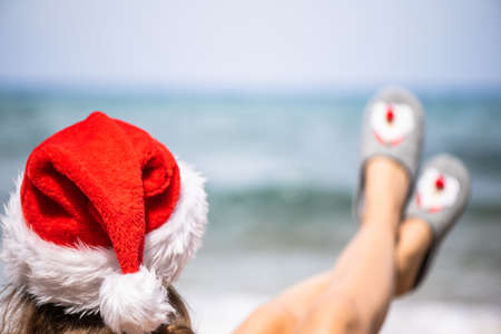 Christmas sea holiday. Woman in santa claus hat and slippers relaxing on paradise beach island. New yearの写真素材