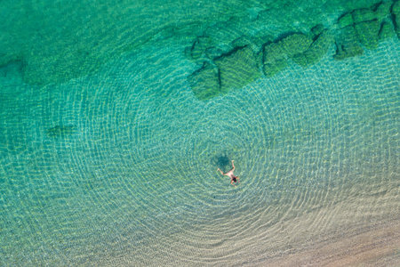 Young woman in a swimsuit swimming in sea water on the beach. View from above. Top, drone view