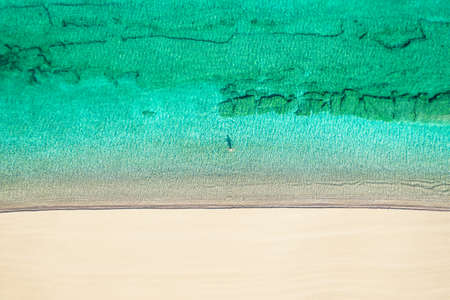 Relaxing aerial beach view with calm sea water and stone, slabs, lump, coral. Summer vacation. Blue ocean lagoon, sea shore, coastline. Drone, copter top view.の写真素材