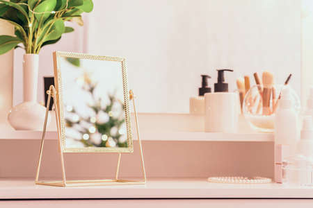 Reflection of christmas tree, light bulbs, in table mirror on woman dressing table with make up accessoriesの写真素材