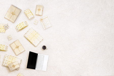 Christmas. Online shopping. Laptop among the many wrapped gifts in white gold wrapping paper on the...