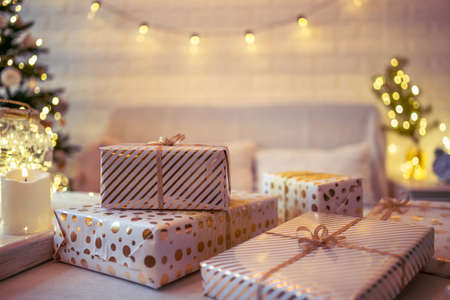 Woman sitting on couch near christmas tree. Female legs, feet in winter woolen socks putting on the table and relaxing after packing handmade gift boxes. Presents for family.の写真素材