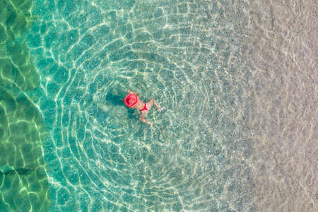 top, aerial view. Young beautiful woman in white bikini swimming in sea water on the sand beach. Drone, copter photo. summer holidays. view from above.の写真素材