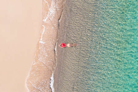 top, aerial view. Young beautiful woman in white bikini swimming in sea water on the sand beach. Drone, copter photo. summer holidays. view from above.の写真素材