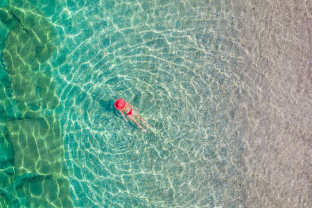 top, aerial view. Young beautiful woman in white bikini swimming in sea water on the sand beach. Drone, copter photo. summer holidays. view from above.の写真素材