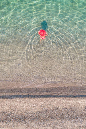 top view. Young beautiful naked woman in a hat swimming in sea water on sand beach. Drone, copter photo. summer holiday. view from above.の写真素材