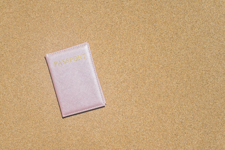 Passport in a cover lying on the sand of the beach. Concept of summer travel, tourism, holiday, vacation.の写真素材