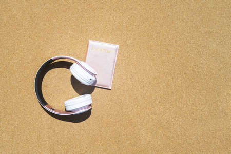 Passport in a cover, headphones lying on the sand of the beach. Concept of summer travel, tourism, holiday, vacation.の写真素材